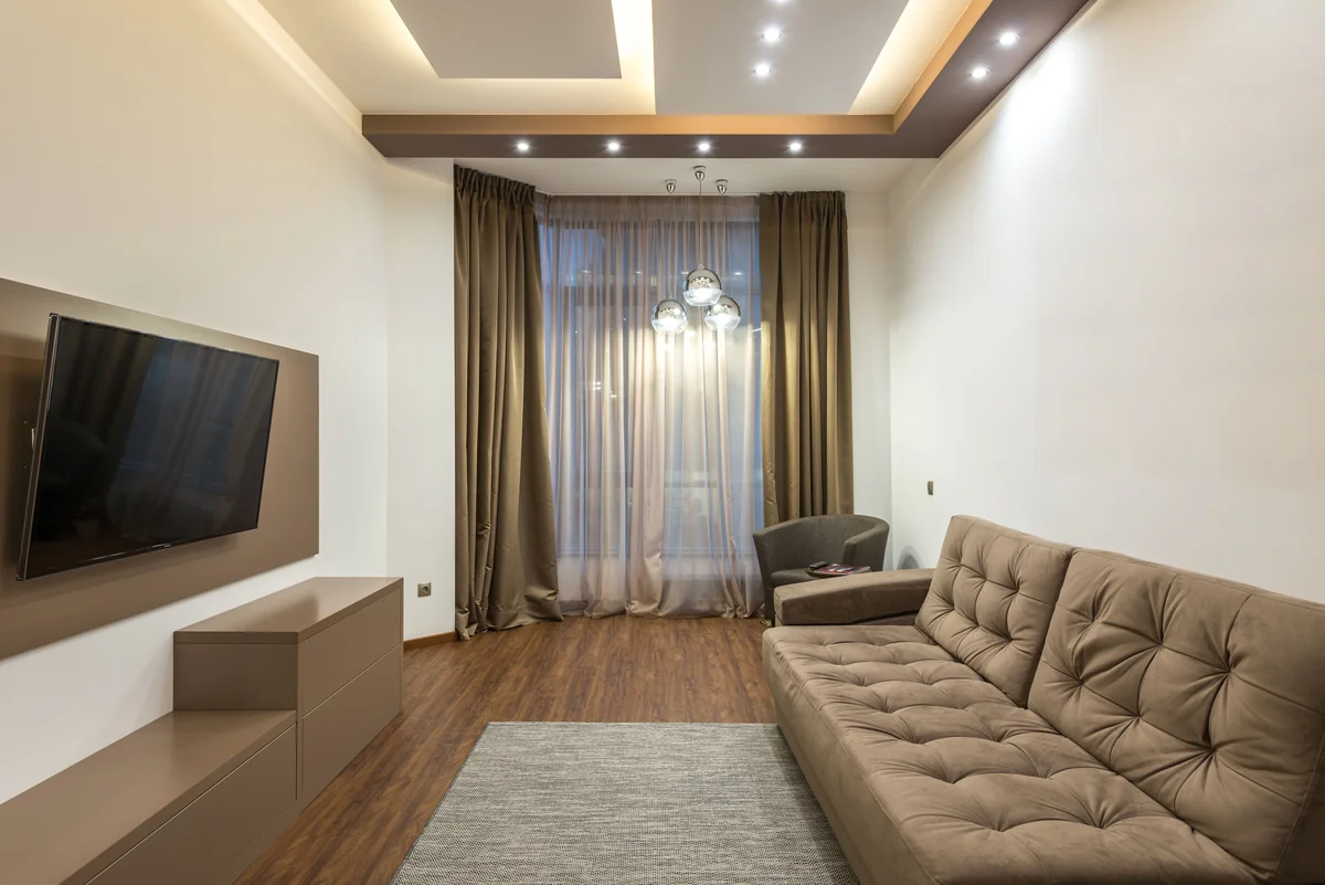 Modern living room with a wall-mounted television and beige furniture
