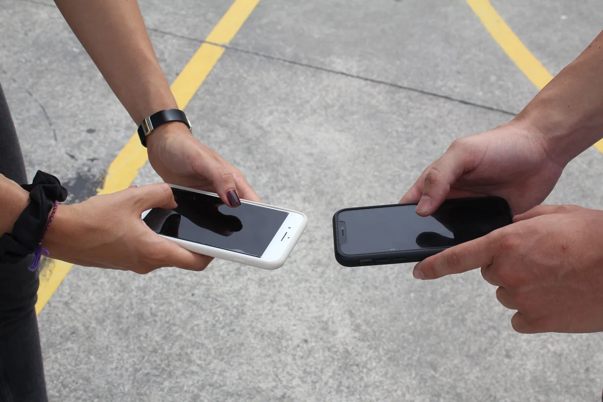 Bir yayın uygulaması seçerken iki akıllı telefon ekranını yan yana karşılaştıran kişi