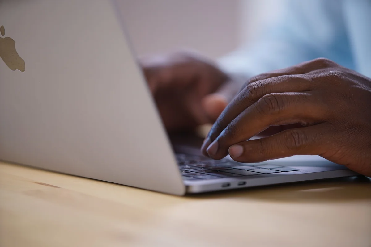 Uomo che digita sulla tastiera di un MacBook a una scrivania