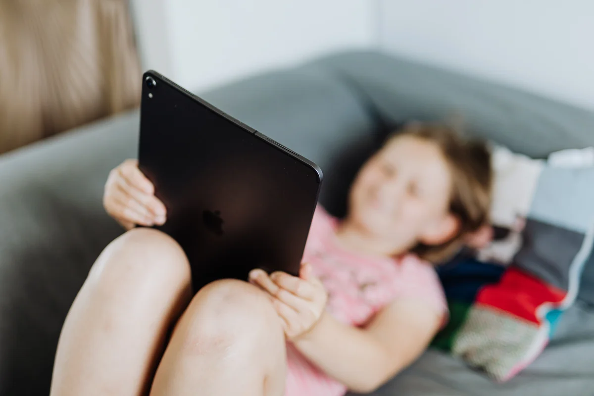 Kanepede uzanırken bir iPad tutan çocuk