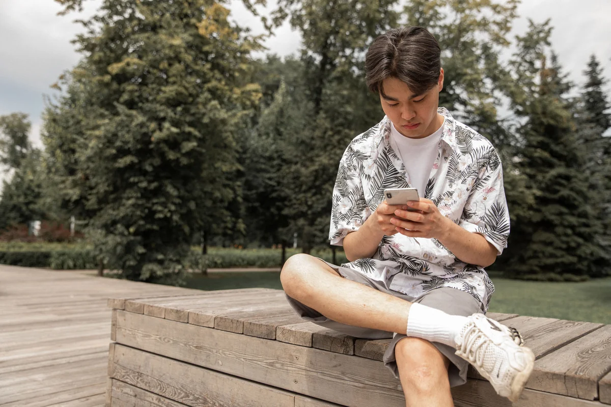 Persoon die buiten zit en kijkt naar een video die afspeelt op een iPhone-scherm