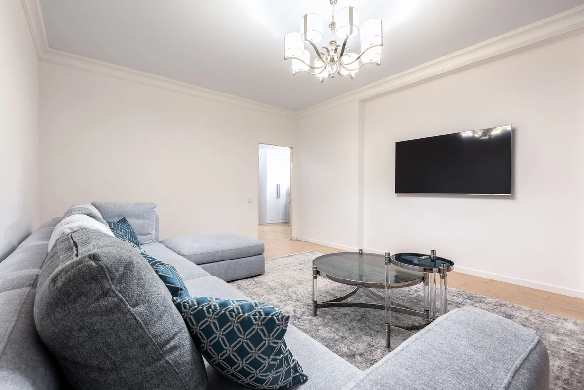 Salotto moderno con una televisione a parete e un divano grigio