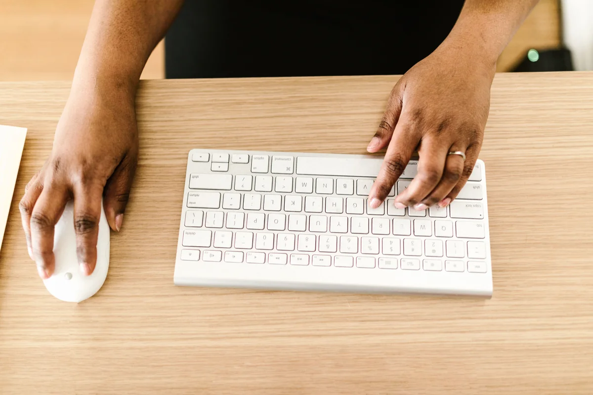 Overhead view of hands typing on a computer keyboard next to a mouse