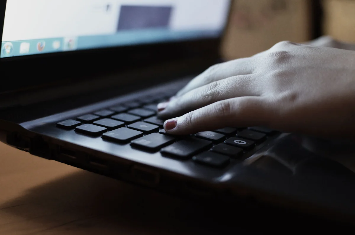 Close-up of hands typing on a laptop keyboard in an office