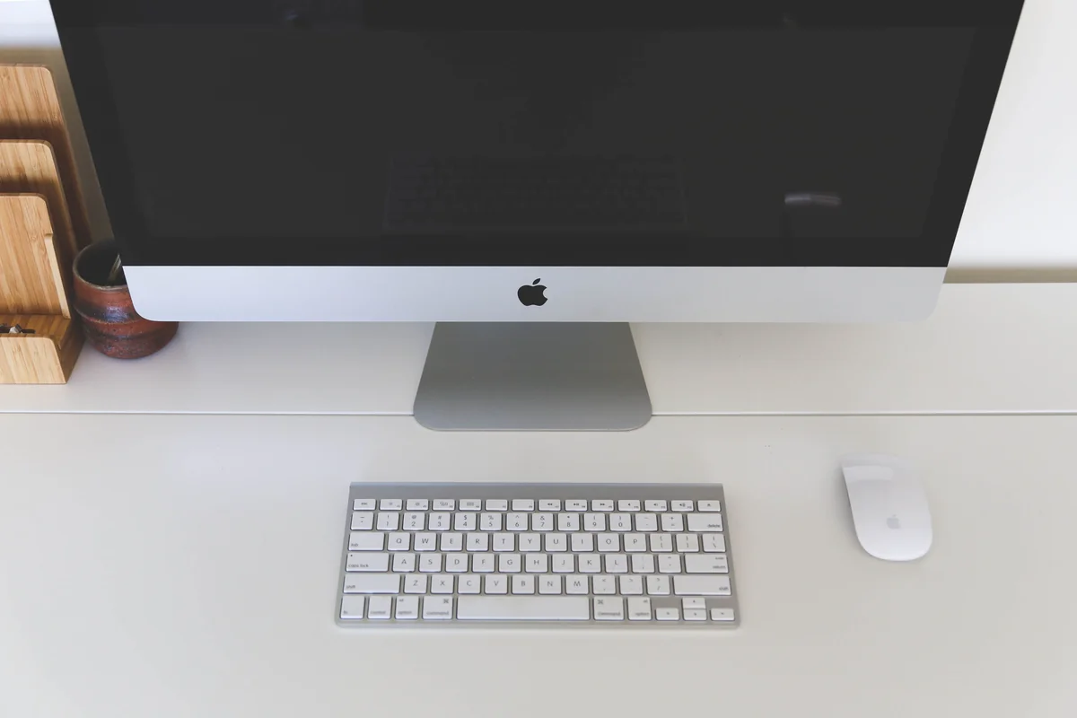 Person sitzt an einem Schreibtisch mit einem iMac-Desktop-Computer