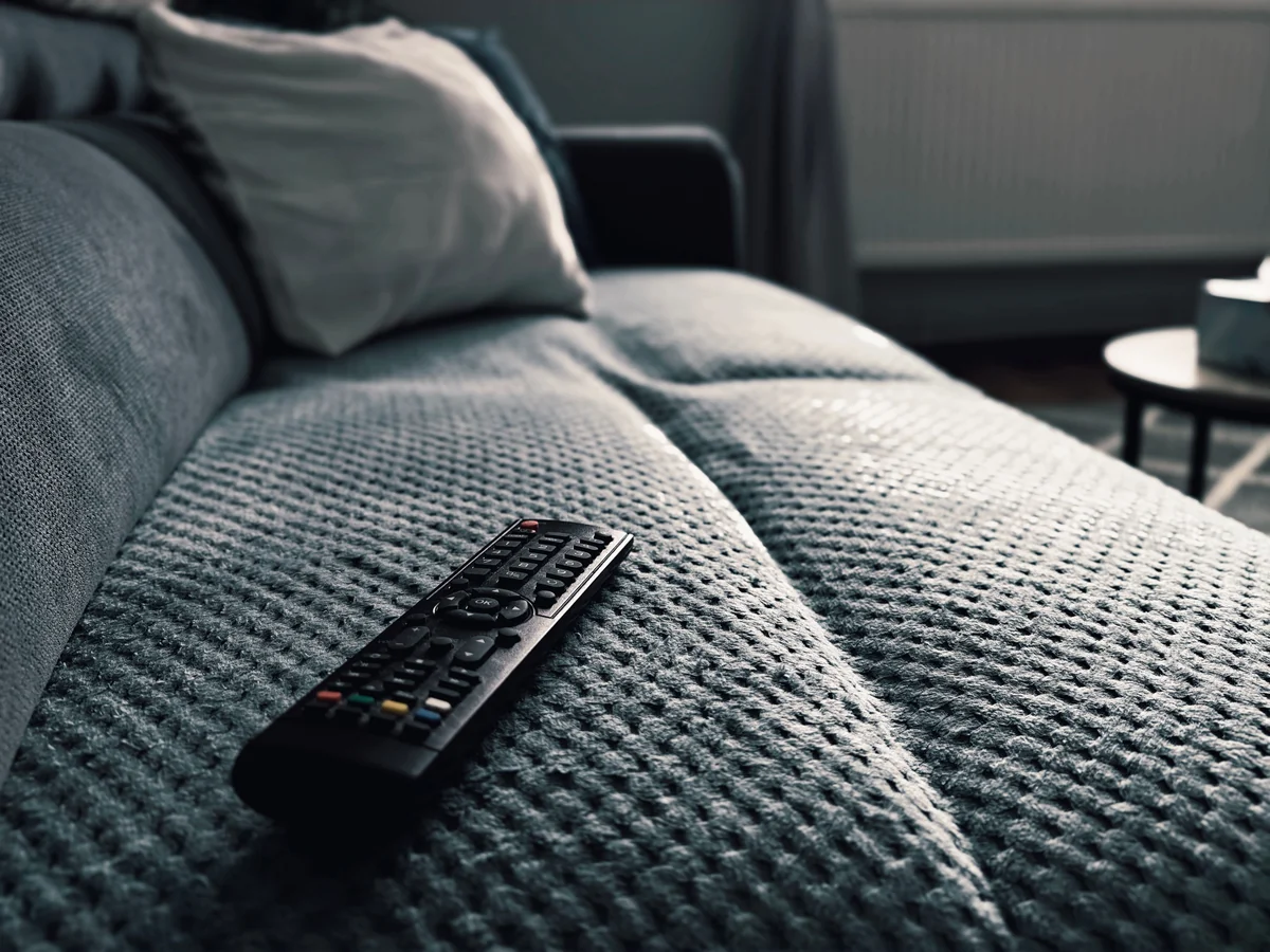 Fjärrkontroll riktad mot en TV som visar en programguide i ett vardagsrum