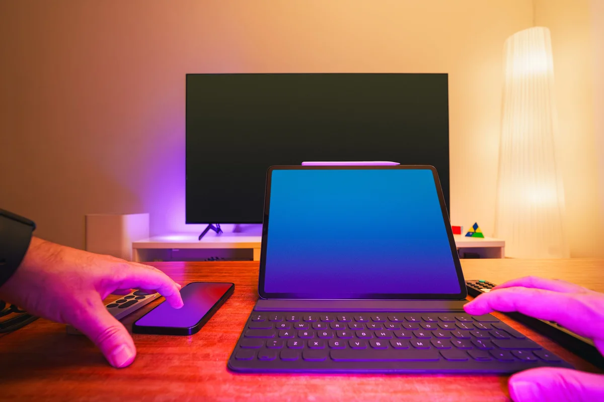 Person hält eine TV-Fernbedienung, während in der Nähe ein Laptop-Bildschirm sichtbar ist