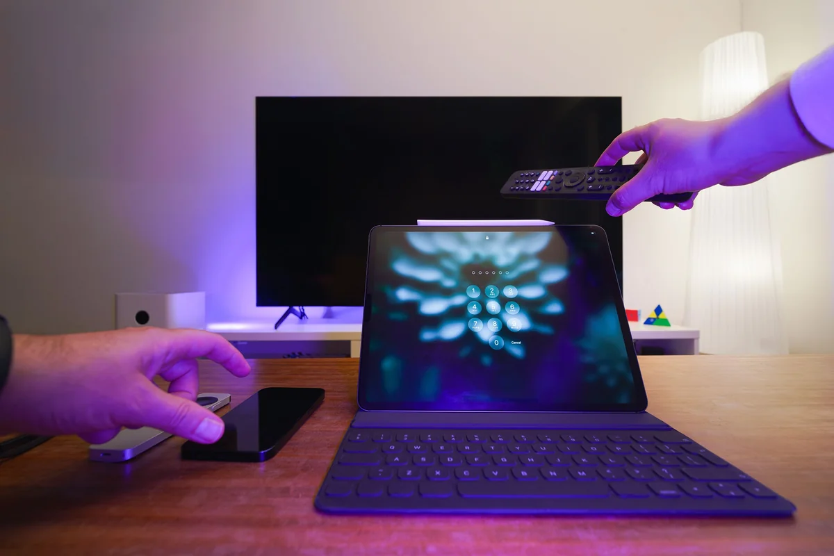 Bir oturma odasında yayın uygulaması kurarken tablet ve TV kumandası tutan kişi