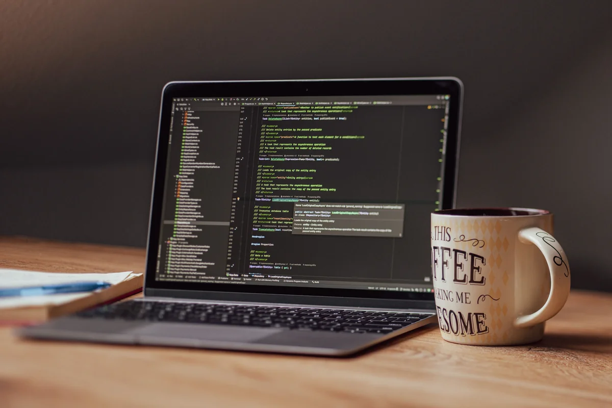 Laptop and coffee on a desk, representing the technical, text-editor side of building an M3U playlist