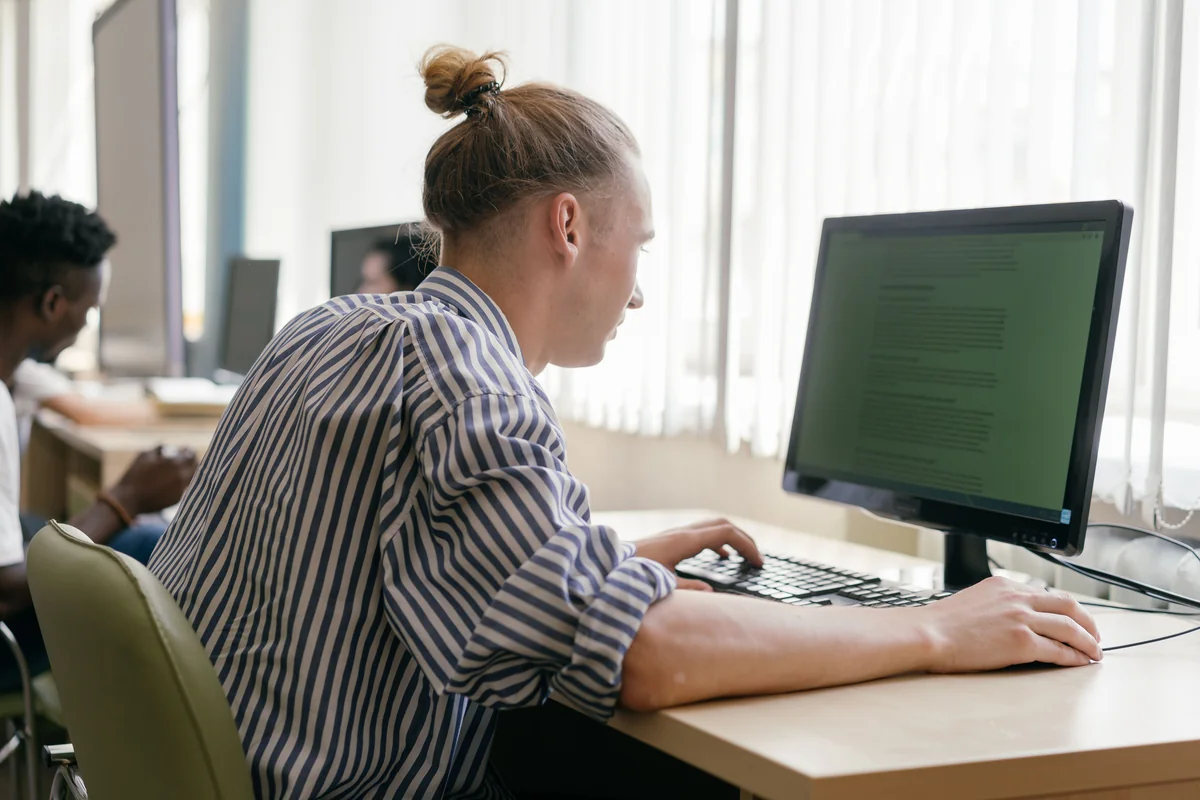 Person sitzt an einem Schreibtisch und nutzt ein Desktop-Computer-Setup